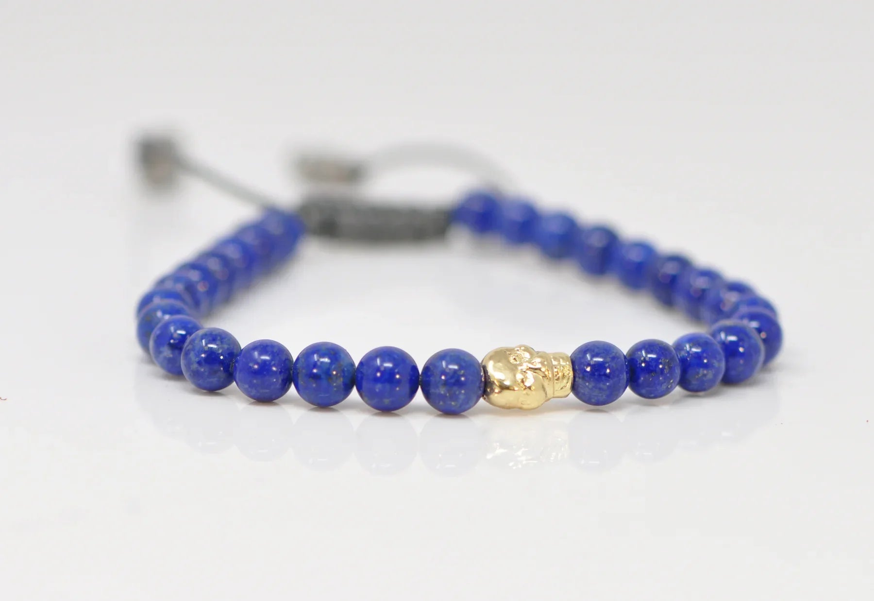 Art deco bangle bracelets with bold lines and shapes for a vintage-inspired flair-Beaded Pull Bracelet With Blue Lapis and Gold Skull Detail